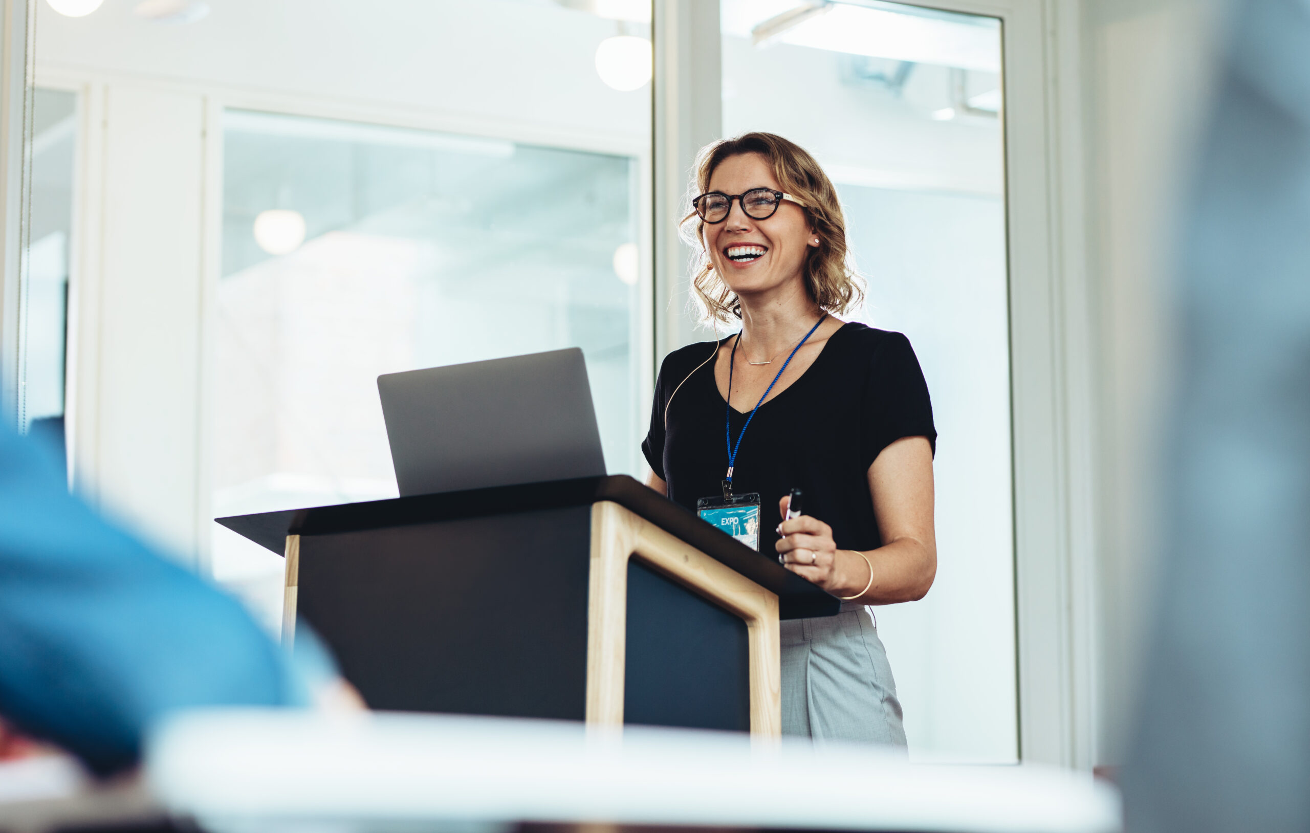 Businesswoman,Standing,At,Podium,With,Laptop,Giving,A,Speech.,Successful LifeSpan Resources